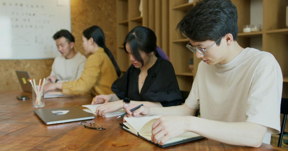Overseas Koreans Scholarship Students studying together in a classroom and taking notes. This is an ideal representation of students of the Overseas Koreans Scholarship in South Korea.