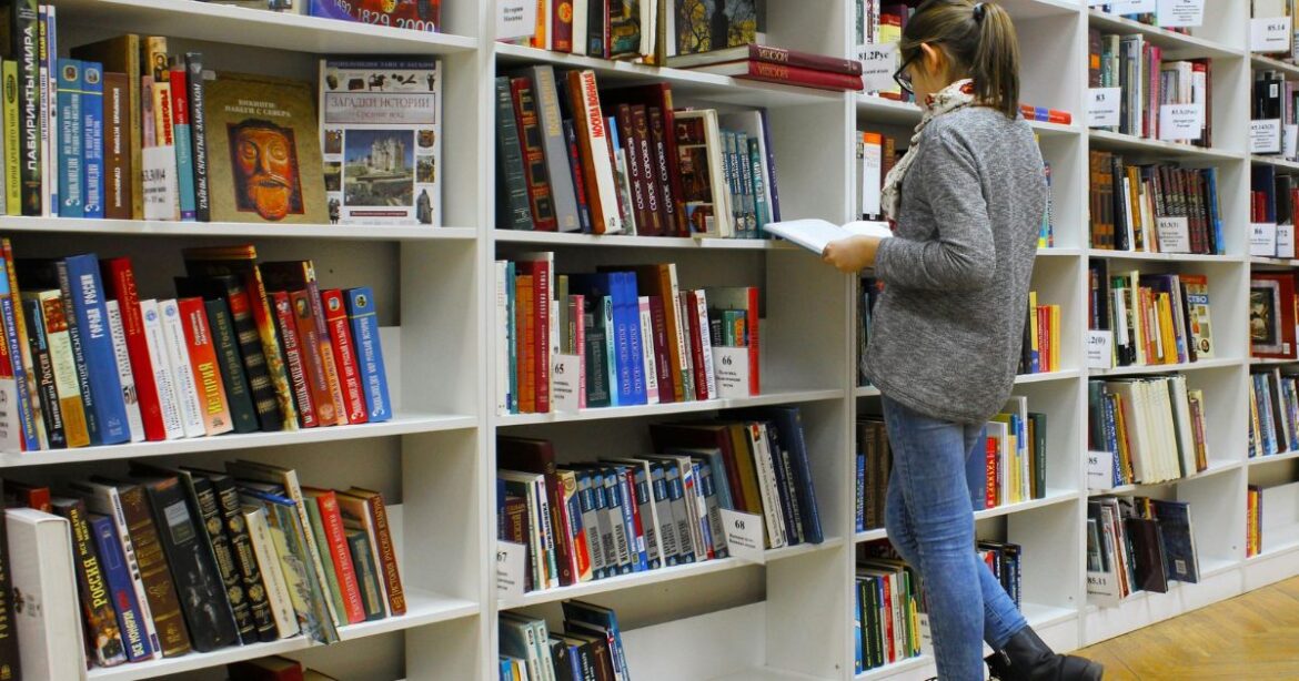 University of Calgary International Entrance Scholarship A student reading a book in a well-stocked library, representing academic excellence and opportunities like the Calgary International Entrance Scholarship.